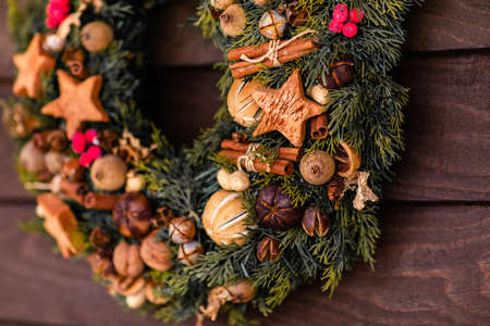 Traditional Christmas wreath made of fir branches, decorated with ginger cookies, cinnamon, nuts, berries, bells and a beautiful bow.の写真素材
