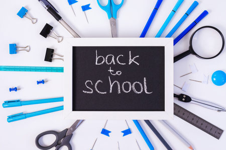 Back to school background with white frame, colorful pencils, square ruler, scissors, clips on...