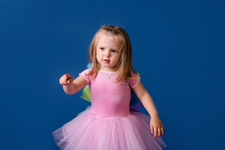Happy little funny emotional child girl in cute Christmas pink pony costume on blue colored...