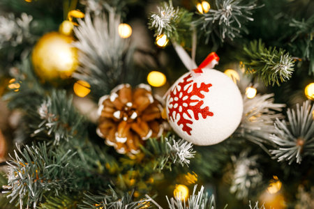 A close-up of a pinecone and a ball with a snowflake on a branch of a Christmas Eveの写真素材