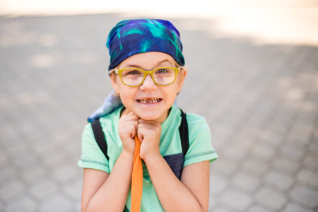 A funny little boy in glasses and a bandana, wearing a green t-shirt and denim shorts, having fun...