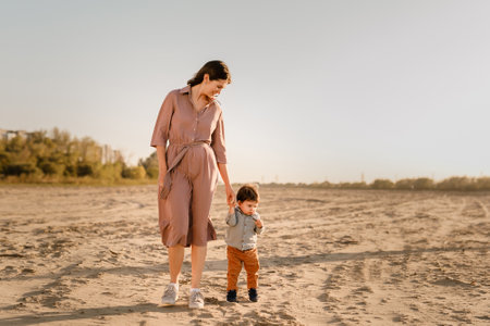 Portrait of loving mother and his one year old son walking and playing with sand.の写真素材