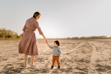 Portrait of loving mother and his one year old son walking and playing with sand.の写真素材