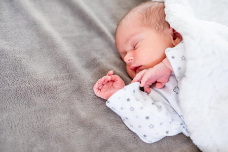 Baby newborn sleeping covered on gray woolen blanket