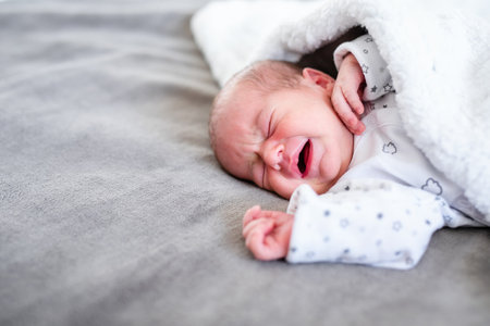 Baby newborn sleeping covered on gray woolen blanketの写真素材