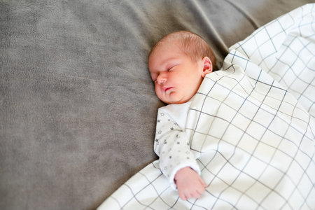 Peaceful baby lying on a bed while sleeping in a bright room.