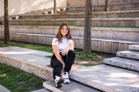 A 16-year-old girl in a school uniform sits on the steps of the street.の写真素材