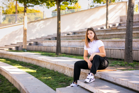 A 16-year-old girl in a uniform sits on the steps.の写真素材