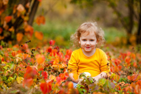Happy little girl in yellow shirt enjoying autumn nature.の写真素材