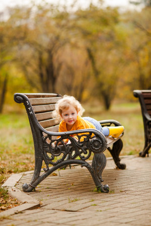 Happy little girl in yellow shirt enjoying autumn nature.の写真素材