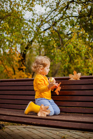 Little girl with curly hair enjoying autumn in a yellow shirt.の写真素材