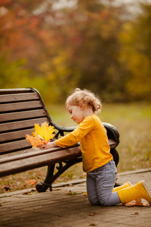 Happy little girl in yellow shirt enjoying autumn nature.の写真素材