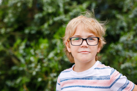 A smiling blonde boy with oversized glasses poses for a portrait.の写真素材