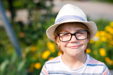 A portrait of a young boy with blonde hair, large glasses, and a straw hat.の写真素材