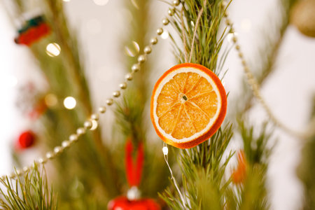 DIY Christmas tree decoration, dried orange on natural pine branches, beads and glitter in the background.の写真素材