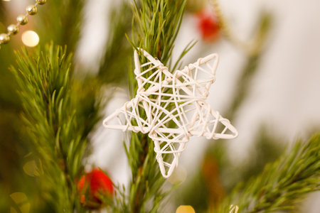 DIY Christmas tree decoration, straw white star on natural pine branches, beads and glitter in the background.の写真素材