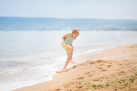 Excited girl on the beach with waves in the background.の写真素材