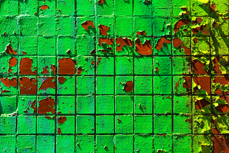 Architectural background made of painted green mosaic wall with peeling paint.の写真素材