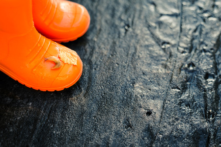 Close up of orange rainboots with fallen leaf and slug on it. Wet dark background. Soft focus.の写真素材