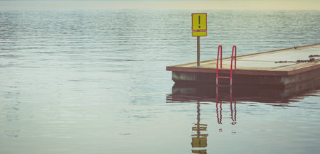 Wooden pier with handrails and sign "attention"の写真素材