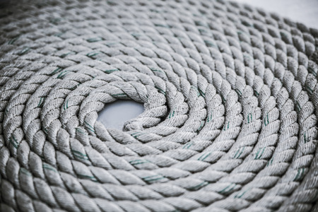 Old worn-out mooring rope rolled in a circle on white background. Close up.の写真素材