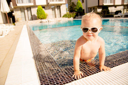 Portrait of a cute blonde baby girl, getting out of swimming pool.の写真素材
