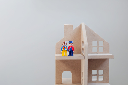 Toy figures of men and women standing next to each other in a wooden house. Symbol of family, property and well-beingの写真素材