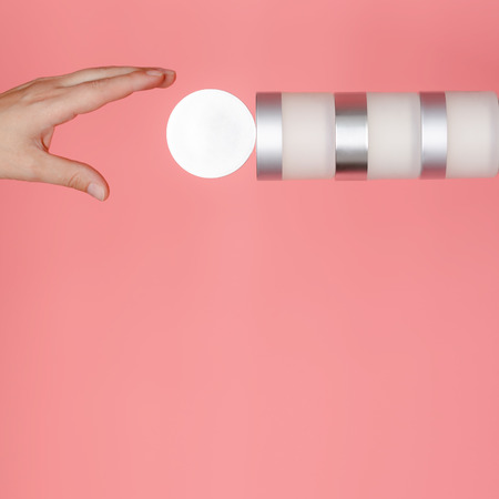 The female hand reaches for a stack of round jars with cream and serum to nourish and moisturize the skin.の写真素材