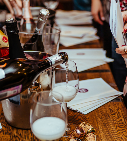 Moscow, Russia-March 30, 2019: wine tasting: on a wooden table there are silver buckets for cooling wines with bottles of champagne, there are brochures and glasses in which champagne is poured.のeditorial素材