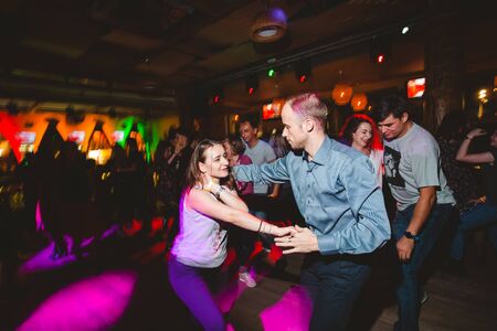 MOSCOW, RUSSIAN FEDERATION - OCTOBER 13, 2018: A middle-aged couple, a man and a woman, dance salsa among a crowd of dancing people in a nightclub Tiki bar. Long exposure, blurred motion.のeditorial素材
