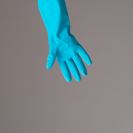 A hand in colorful protective rubber glove. Spring cleaning concept.の写真素材