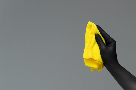 A hand in a rubber glove holds a bright microfiber duster on a neutral background. Ð¡oncept of bright spring, spring cleaning.の写真素材