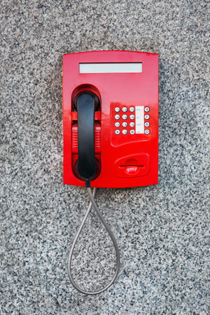 Street pay phone red on the wall.