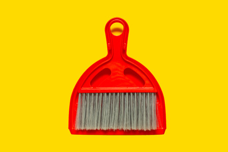 Red dustpan and brush lying on yellow background. In the style of pop art. Top view.の写真素材