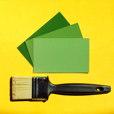 Clean paintbrush and three card samples of green colors on yellow background.の写真素材