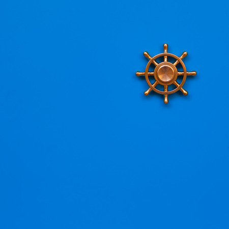 Copper yacht steering wheel on blue background. Symbol of leadership. Copy space.の写真素材