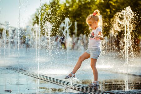 MOSCOW, RUSSIAN FEDERATION - JULY 29, 2018: A little girl with her foot touches the water jet of a pedestrian fountain on the Crimean embankment in Muzeon Park.のeditorial素材