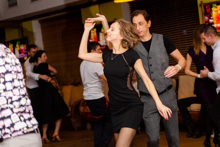 Moscow, Russia-January 19, 2019: A middle-aged couple, a man and a woman, dance salsa among a crowd of dancing people in a nightclub Tiki bar.のeditorial素材