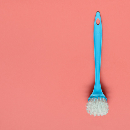 Pale blue brush for washing dishes lying on living coral background. In the style of pop art. Top view. Copy space.の写真素材