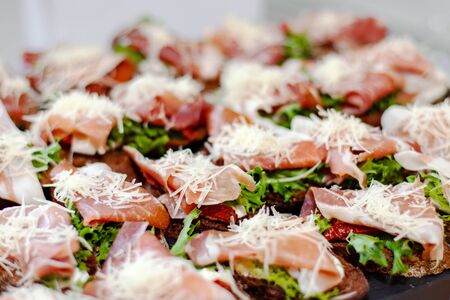 Snack plate at the event: prosciutto sandwiches, sun-dried tomatoes, fresh lettuce and grated cheese.の写真素材