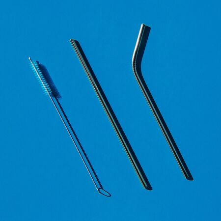 A set of reusable accessories for drinks. A set of steel straws and a cleaning brush. Blue background, top view. The zero waste concept.の写真素材