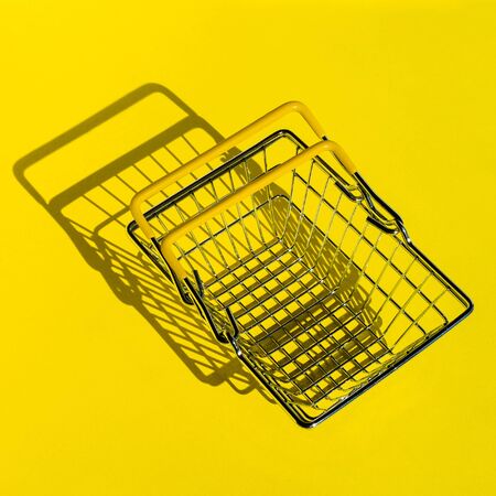Metal mesh shopping basket in a supermarket. The view from the top. Yellow background.の写真素材
