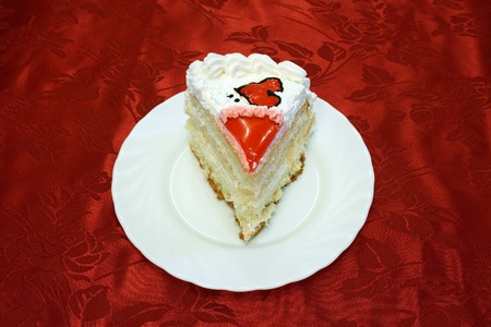 white cake decorated with red hearts on a red background on a white plate cuttedの写真素材