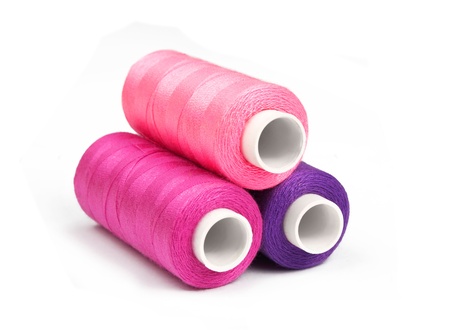 Pyramid of pink, violet and purple bobbins of thread isolated on whiteの写真素材