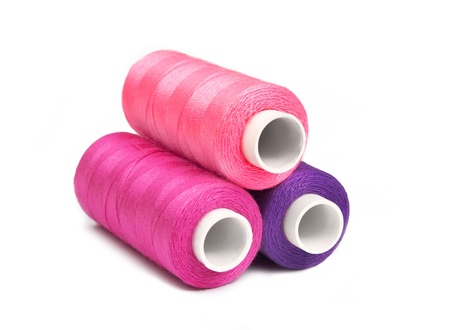 Pyramid of pink, violet and purple bobbins of thread isolated on whiteの写真素材