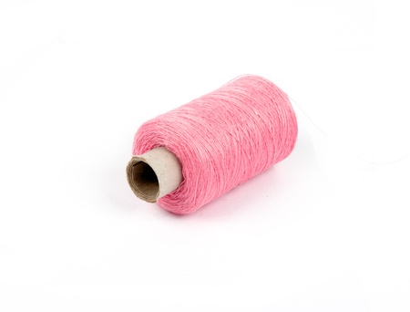 pink bobbin of thread isolated on whiteの写真素材
