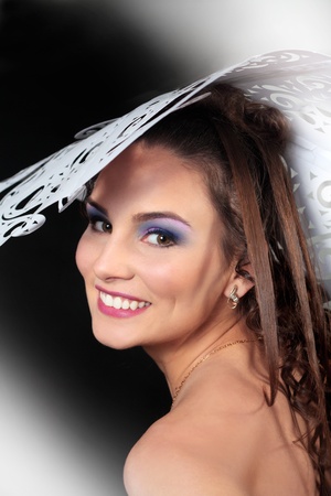 Gorgeous woman smiling in big paper hat isolated over black backgroundの写真素材