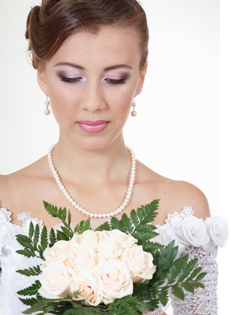 portrait of a beautiful bride looking to a bouquet of flowersの写真素材
