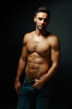 portrait of topless athletic macho man posing over black backgroundの写真素材