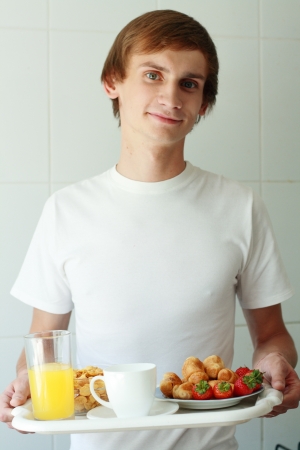 young man holding tray with continental breakfast の写真素材